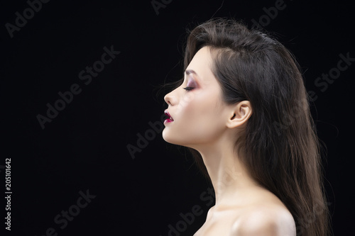 Portrait of a beautiful glamorous brunette girl sideways. Shimmering makeup, red lips. Healthy smooth skin.