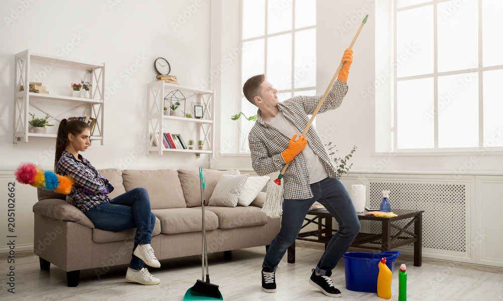 Young couple cleaning home, playing with mop