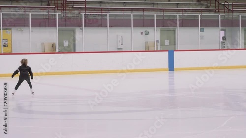 Little girl learning to figureskate during the public ice skating session at indoor ice skating rink photo