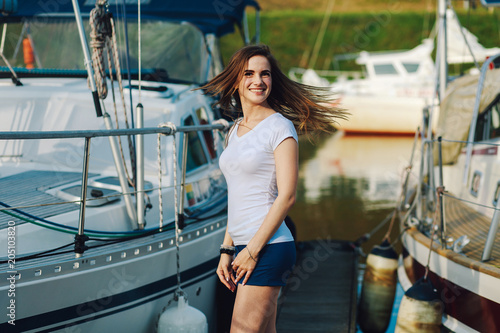 young beautiful girl is smiling at the camera on the background of summer yachts