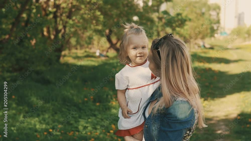 Mother and daughter walking in park, beautiful mom with her little children outdoor on warm summer day in slow motion with copyspace Mother and daughter walking in park, beautiful mom with her little children outdoor on warm summer day in slow motion with copyspace