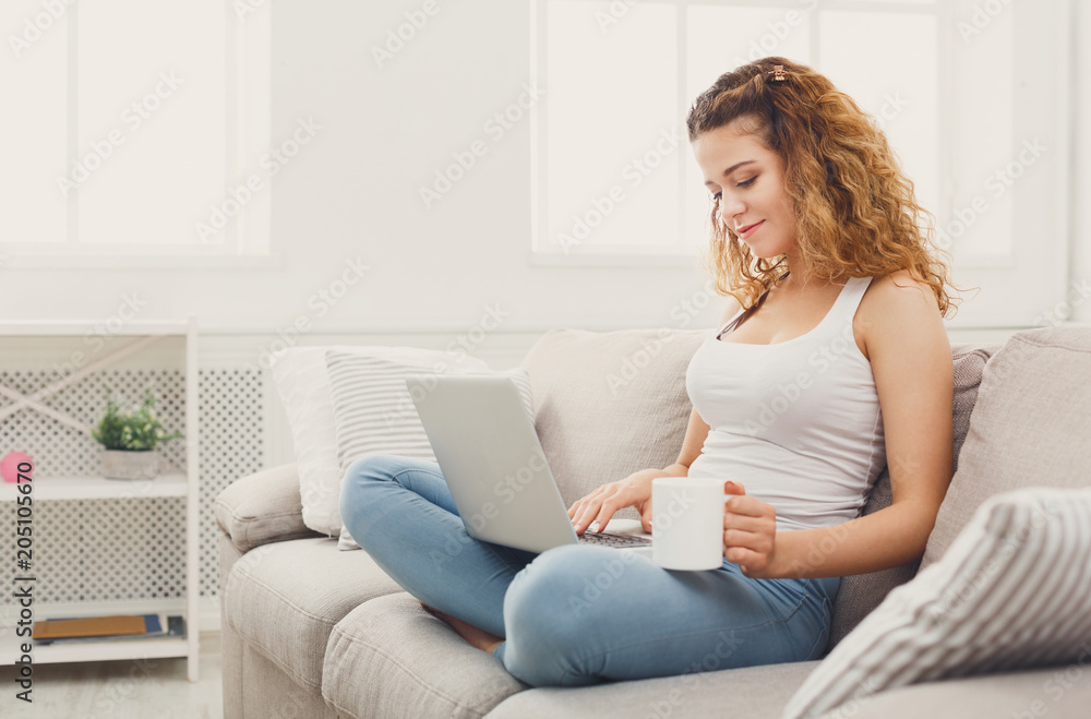 Young girl with laptop sitting on beige couch Young girl with laptop sitting on beige couch