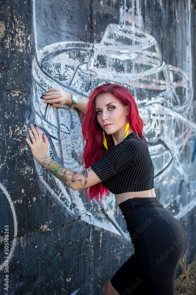 Sexy Redhair Woman In Hooligan Outfit And Sunglasses Posing Against Graffiti Wall Stock Foto
