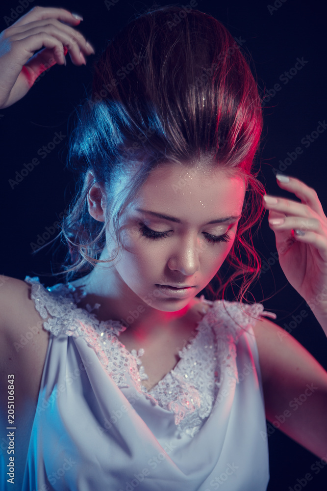 Fototapeta premium Fashion portrait of young elegant girl in white dress. Black background, studio shot.