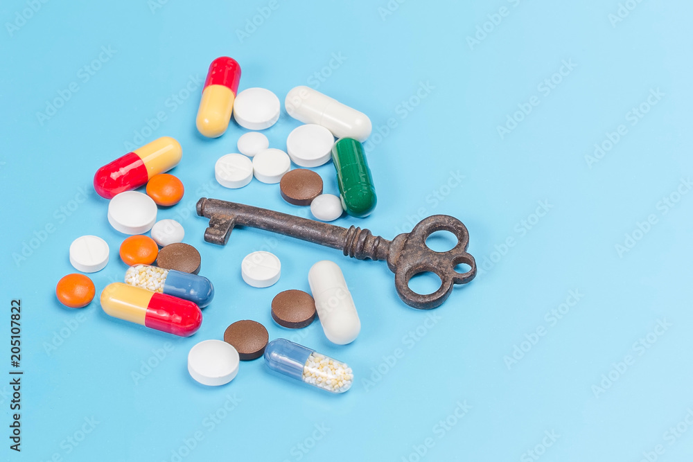 Medications of different colors and shapes with a copper key, on a light blue background Medications of different colors and shapes with a copper key, on a light blue background