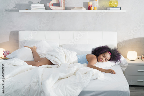 Black Woman Sleeping Alone in Large Bed photo