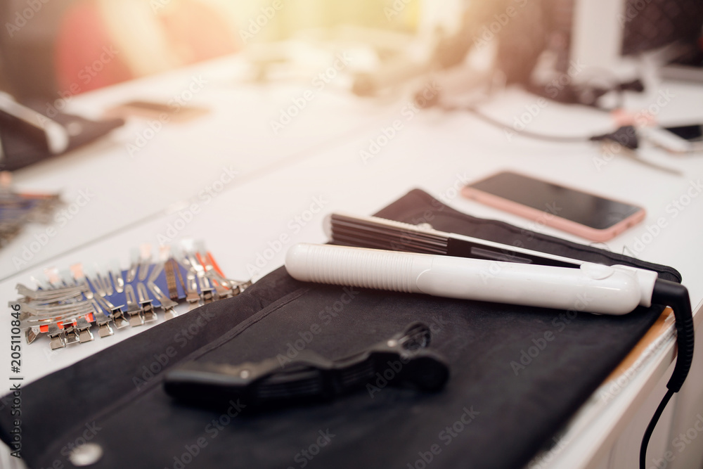 Tool of hairdresser: straightener, clips, hairpins. In background, women make hairstyles Tool of hairdresser: straightener, clips, hairpins. In background, women make hairstyles