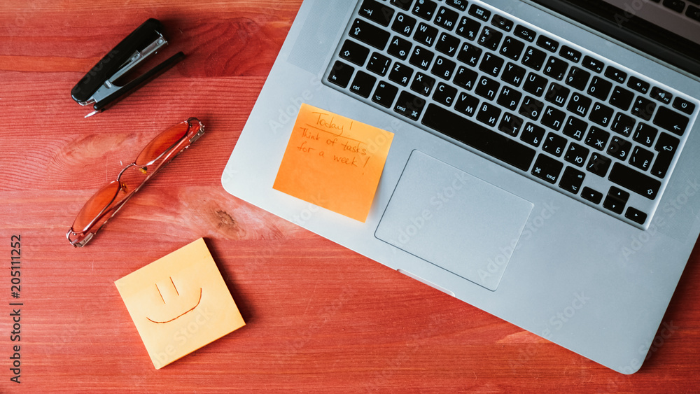 Computer pc, stickers, glasses and stapler lie on a wooden red background