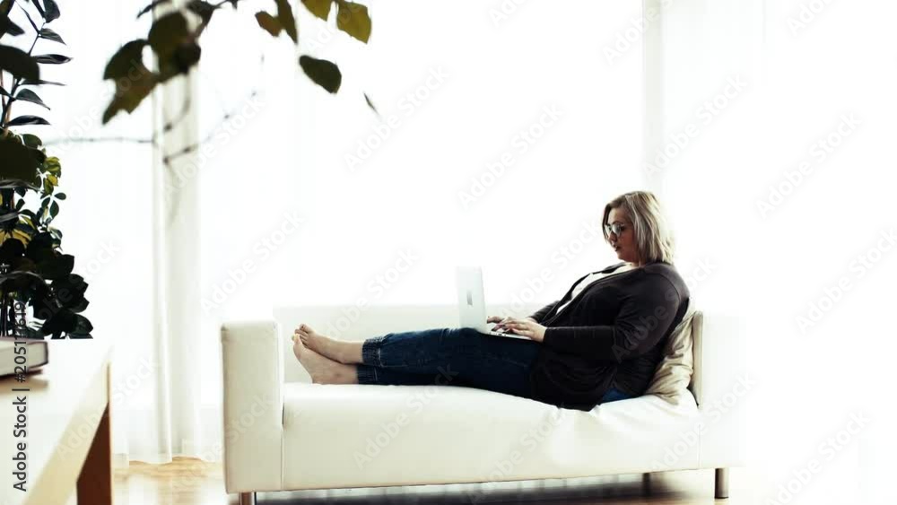 An attractive overweight woman at home, using laptop. An attractive overweight woman at home, using laptop.
