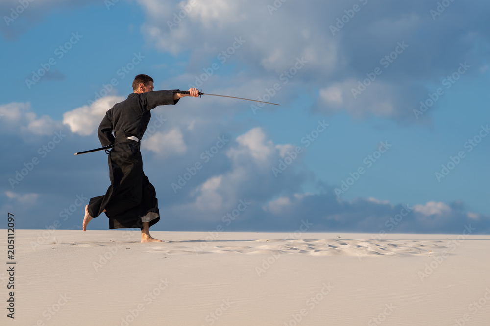 Man practicing Japanese martial art in desert Man practicing Japanese martial art in desert