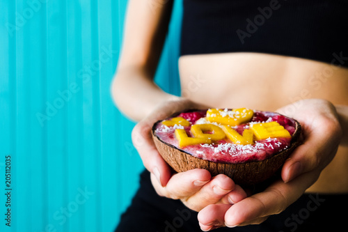 Concept of diet  proper nutrition and health. Thin girl holding a smoothie bowl of fruit on a wooden turquoise background  copy space.