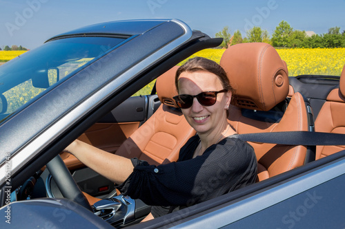 Attractive smiling Brunette Young Woman in a luxury convertible car.
