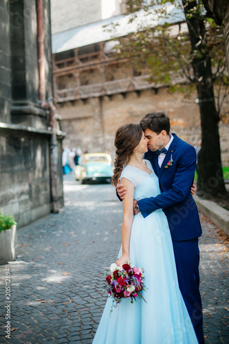 elegant wedding couple gently hugging in sunlight in old courtyard