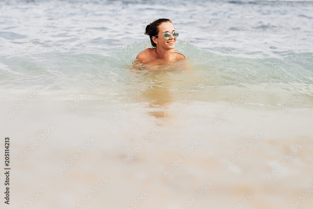 A girl bathes in the sea sunglasses. Young fashion woman on the beach A girl bathes in the sea sunglasses. Young fashion woman on the beach