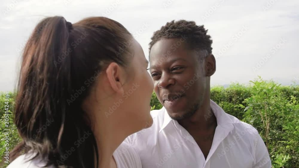 Young happy smiling black man look at woman are communicating outdoors. Close up of multiethnic couple enjoy a date together