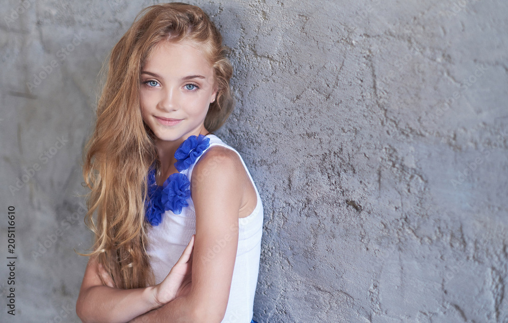 Portrait of a happy little girl model with charming smile posing in a studio.