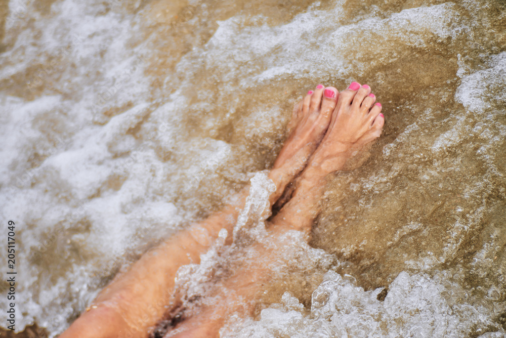 Woman barefoot on the summer beach. close up of a young woman the beach. Travel Concept.Texture background.