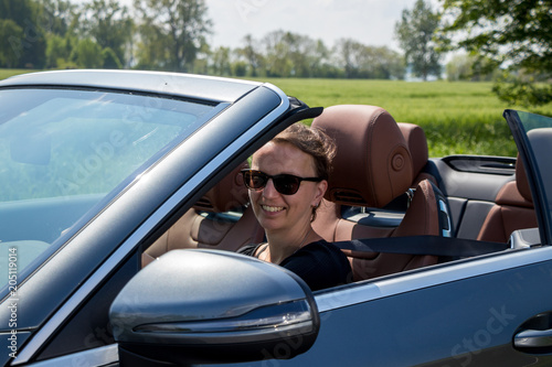 Attractive smiling Brunette Young Woman in a luxury convertible car.