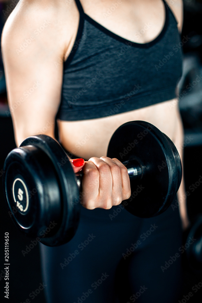Girl doing bicep exercise with dumbbells in gym Girl doing bicep exercise with dumbbells in gym
