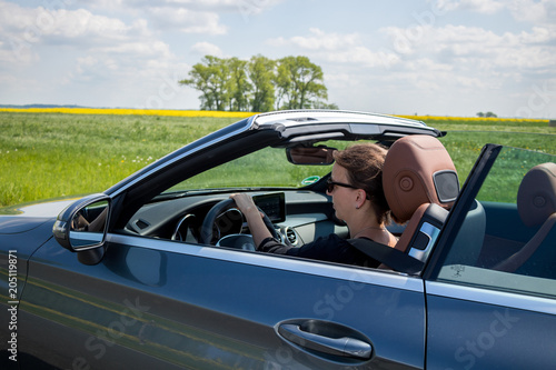 Young woman drive a convertible car on a sunny day