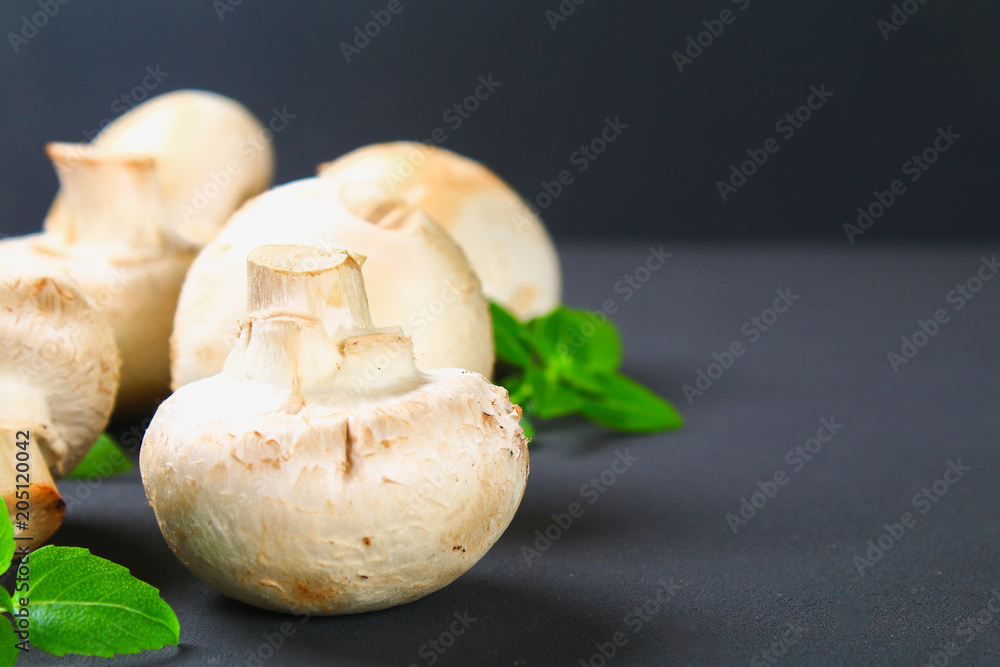 White fresh champignons with parsley on a wooden board on a gray dark table. Mushrooms. Copy the space. Top view. White fresh champignons with parsley on a wooden board on a gray dark table. Mushrooms. Copy the space. Top view.