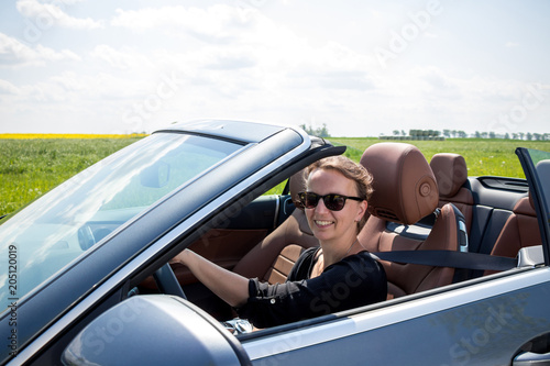 Happy beautiful Woman Driving in Luxury Convertible Sports Car - View with car interior