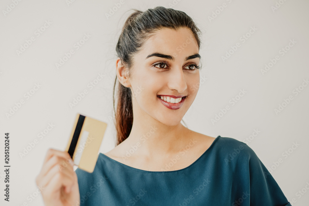 Φωτογραφία Studio portrait of happy young Latin-American woman holding debit or credit card