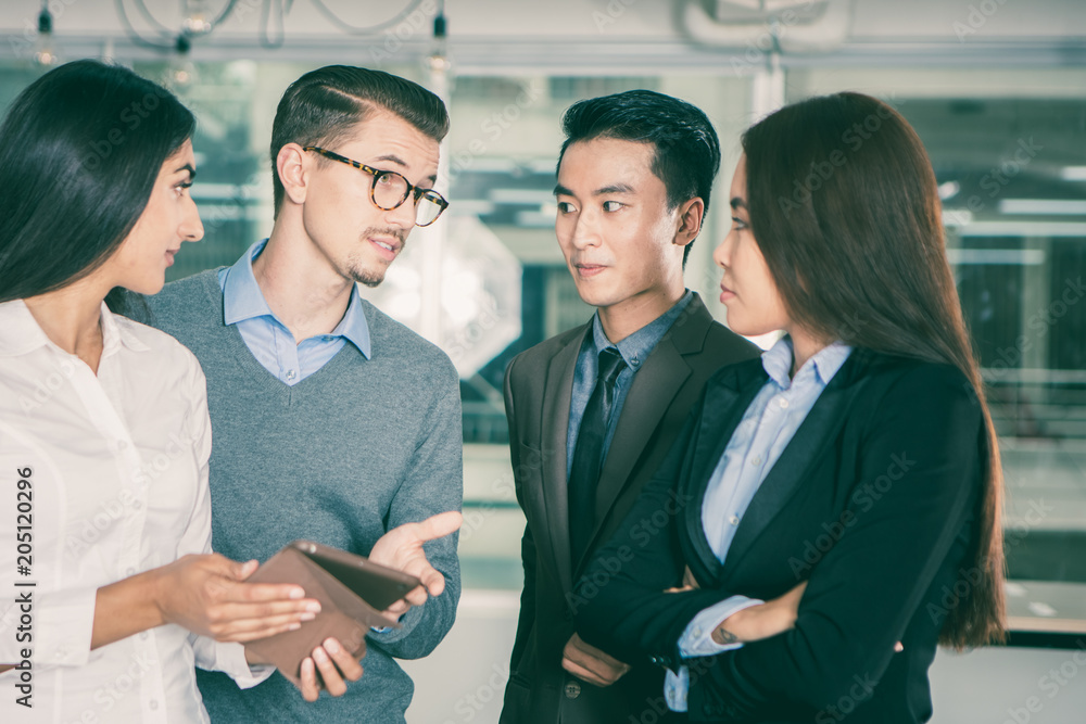 Fotografie Serious young multiethnic business people standing together in office