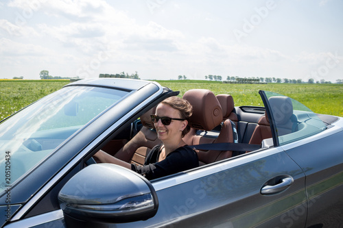 Happy beautiful Woman Driving in Luxury Convertible Sports Car - View with car interior