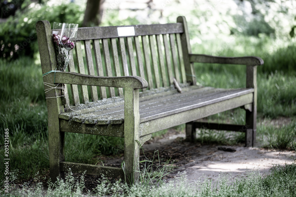 Wooden Memorail Bench in the Park with flower bouquet tied on with string