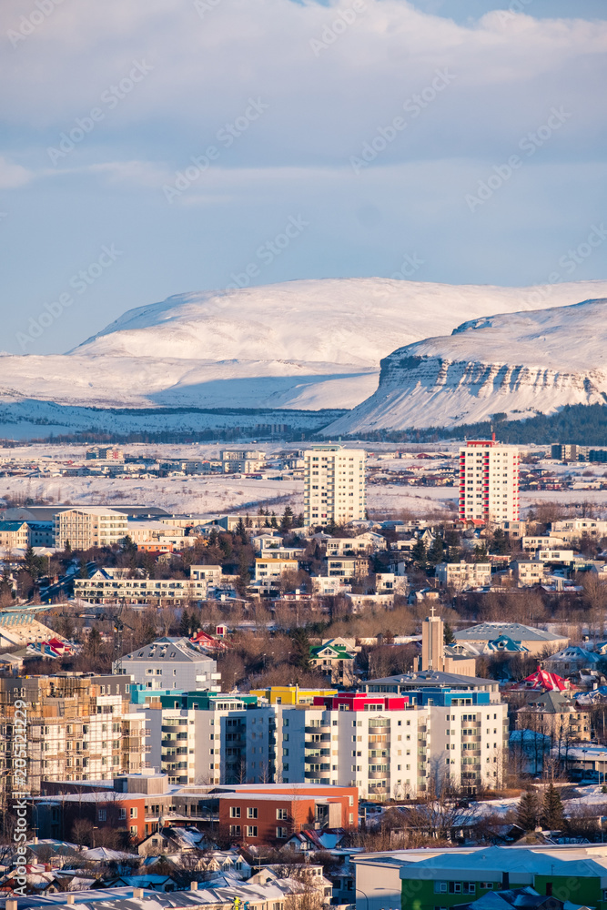 Vertical view of Reykjavik downtown in a golden evening light. Capital city of Iceland Reykjavik in winter surrounded with snow covered mountains.