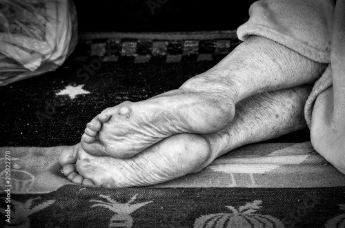 Barefooted homeless or refugee person sleeping on the street with dirty feet skin © Srdjan