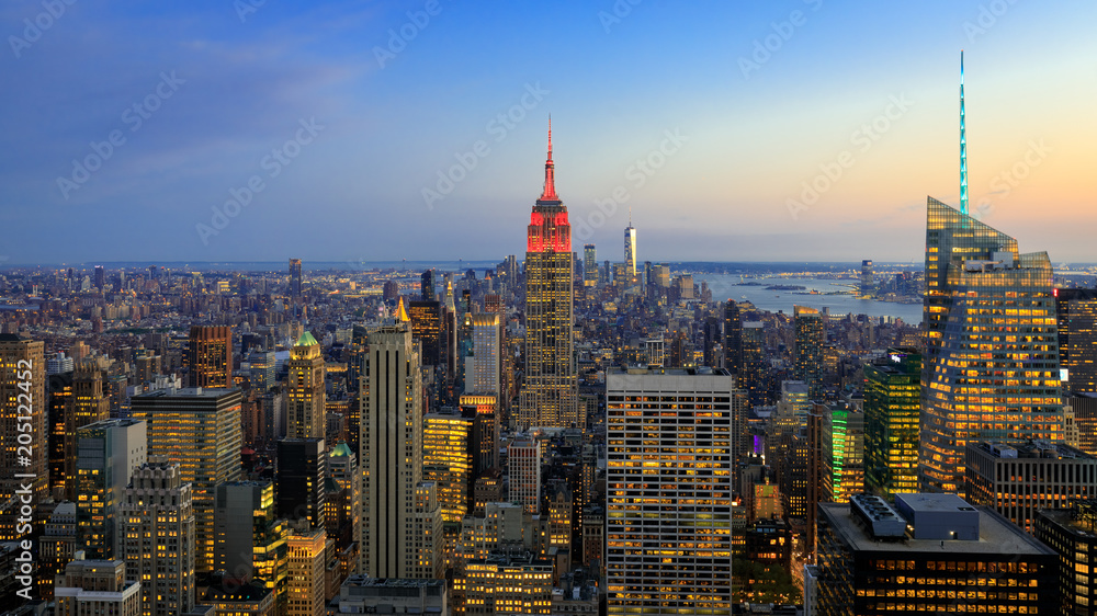 Obraz premium Manhattan downtown skyline with illuminated Empire State Building and skyscrapers at sunset