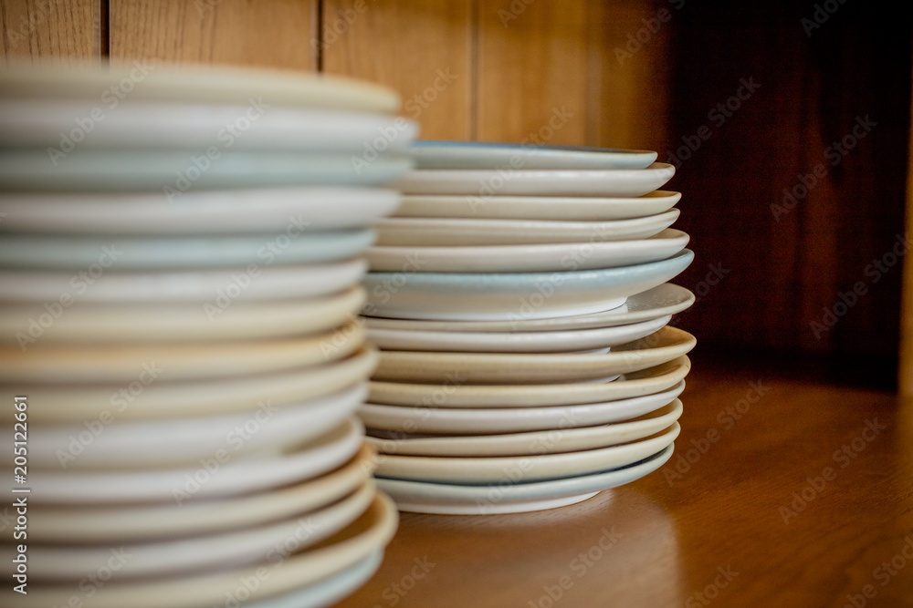 Group of white plates stacked together.Clean plates isolated on wooden shelf.Selective focus. Copy space Group of white plates stacked together.Clean plates isolated on wooden shelf.Selective focus. Copy space