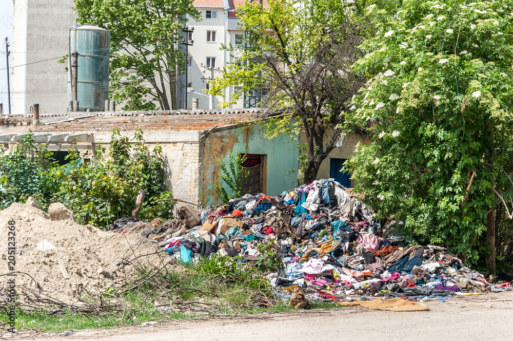 Abandoned rural damaged house in the ghetto near new residential building in the city used as garbage dump with junk and litter in the yard polluting the environment