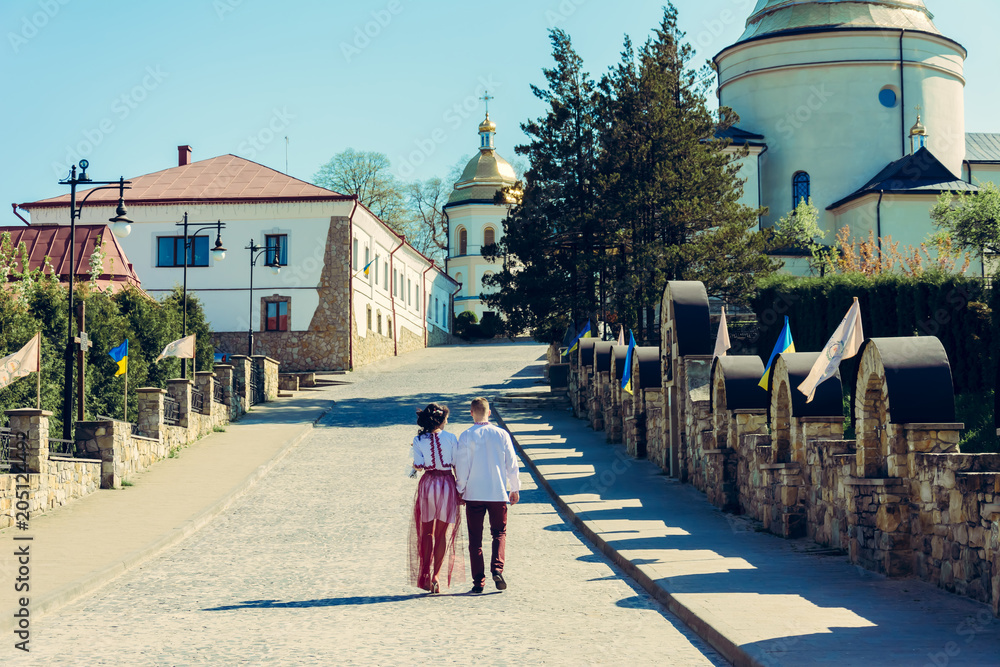 Obraz premium A beautiful young couple goes to the church in embroidery during the wedding