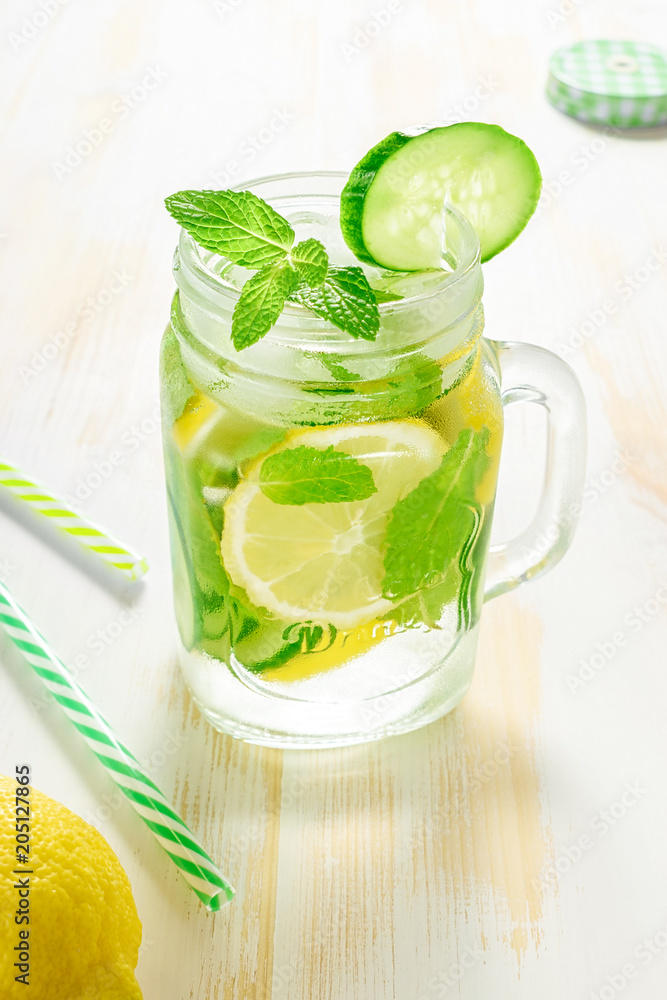 Fototapeta premium Detox water infused with sliced lemon, cucumber and sprigs of mint on wooden background.