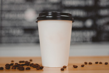 Küchenrückwand glas motiv Kaffee und Kaffeebohnen Weiße Pappbecher Kaffee mit schwarzen Kappen in vorderen Körnern liegen auf dem Tisch. Konzept der Essenslieferung  © Parilov