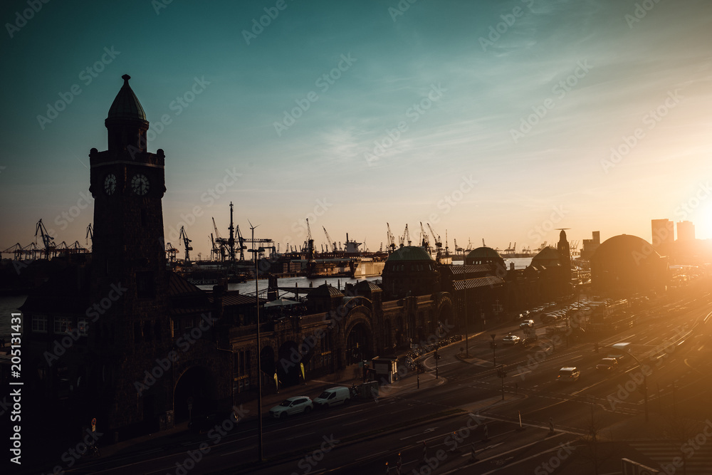 Obraz premium Silhouette of famous Hamburger Landungsbruecken with commercial harbor and Elbe river in late evening sunset light, St. Pauli district, Hamburg, Germany