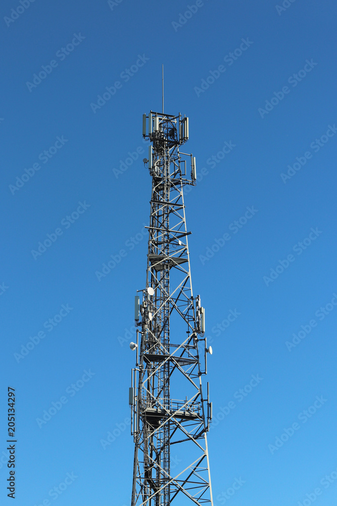 Radio tower with antennas on a blue sky background. Metal construction. Technology building. The technology of wireless information transmission from a distance. Radio tower with antennas on a blue sky background. Metal construction. Technology building. The technology of wireless information transmission from a distance.
