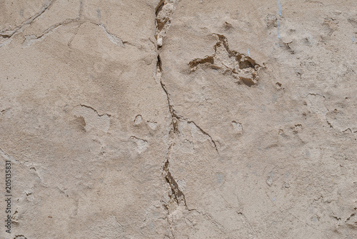 old chipped plaster on the concrete wall, beige texture, background