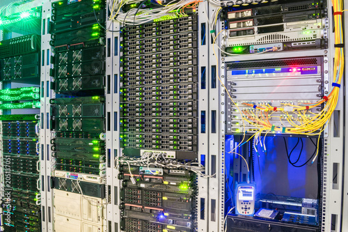 Racks with servers are installed in the server room of the data center. Multiple optical wires connect to the central router. The technical node of the Internet provider