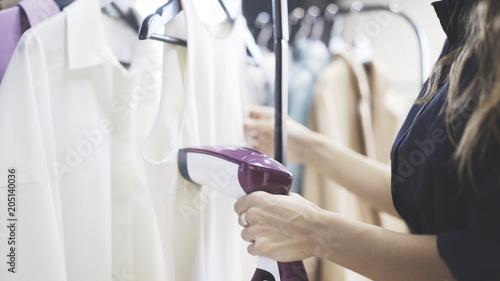 Fotografija Unrecognizable young shop assistant using steam to iron a white shirt in a clothes shop