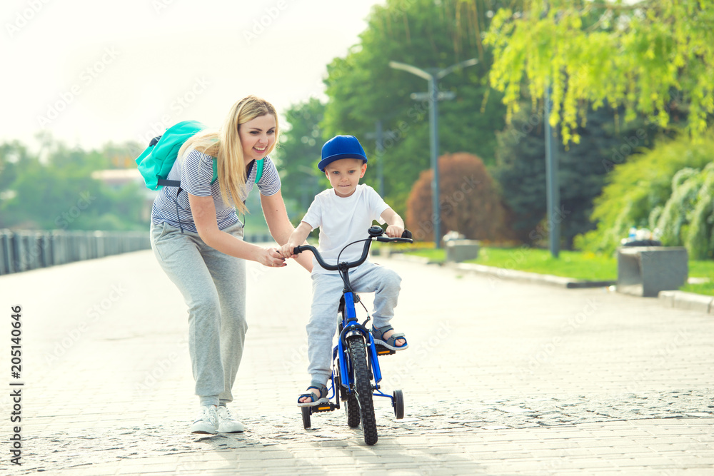 Mother learn his little son to ride a bicycle.	