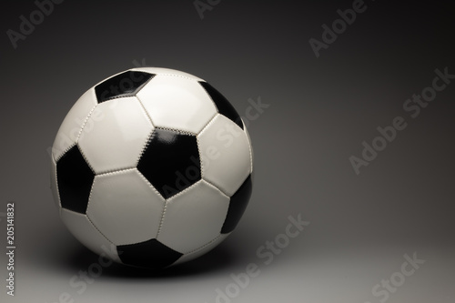 A classic white black soccer ball on a gray gradient background. There is a place for an inscription.