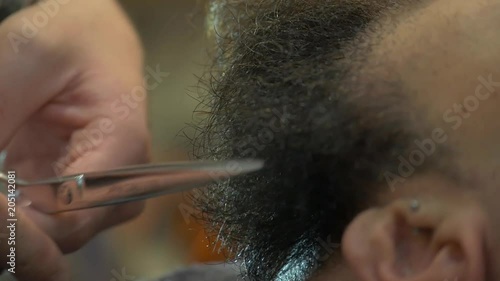 Barber uses scissors on hair, close up