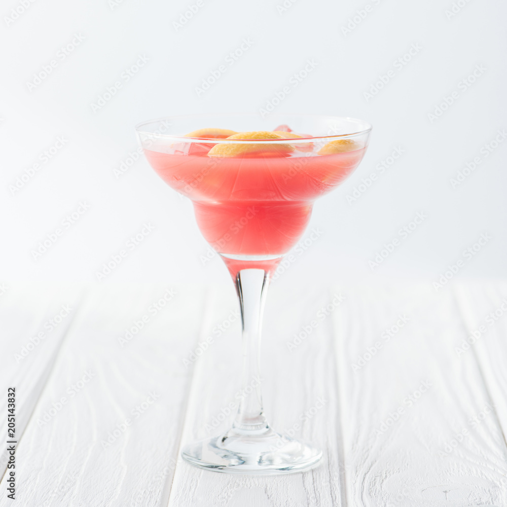 close up view of tasty summer margarita cocktail on white wooden tabletop on grey backdrop