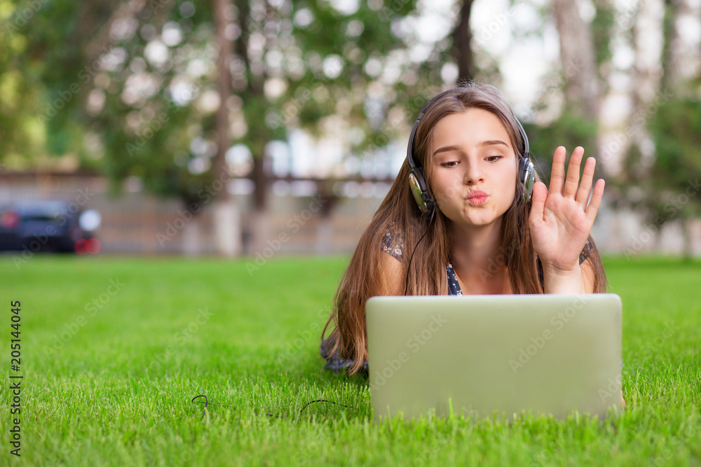 woman having a video call with a laptop and headphones blowing a virtual kiss greeting a friend woman having a video call with a laptop and headphones blowing a virtual kiss greeting a friend