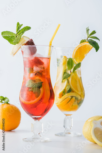 close up view of summer fresh cocktails with strawberry, lemon and orange pieces, mint isolated on white