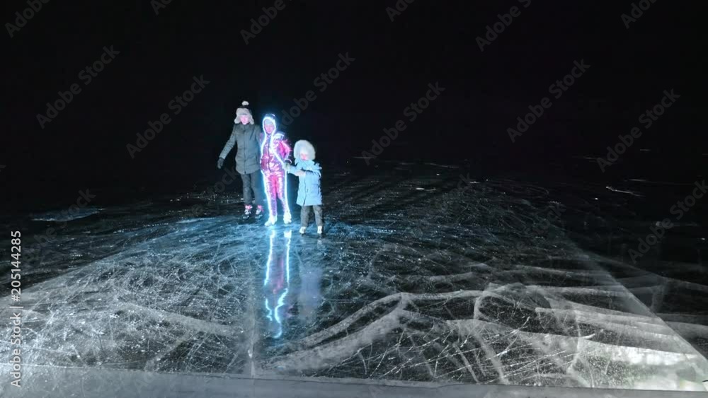 Family is ice skating night. Girls and boys to ride figure ice skates in nature. Mother daughter and son riding together on ice in cracks. Outdoor winter fun for athlete nice winter weather. People on Family is ice skating night. Girls and boys to ride figure ice skates in nature. Mother daughter and son riding together on ice in cracks. Outdoor winter fun for athlete nice winter weather. People on
